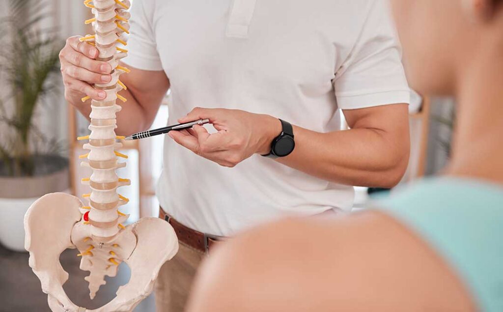 A chiropractor gently adjusting an adult patient's back in a medical office setting.