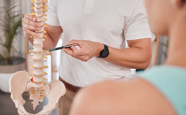 A chiropractor gently adjusting an adult patient's back in a medical office setting.