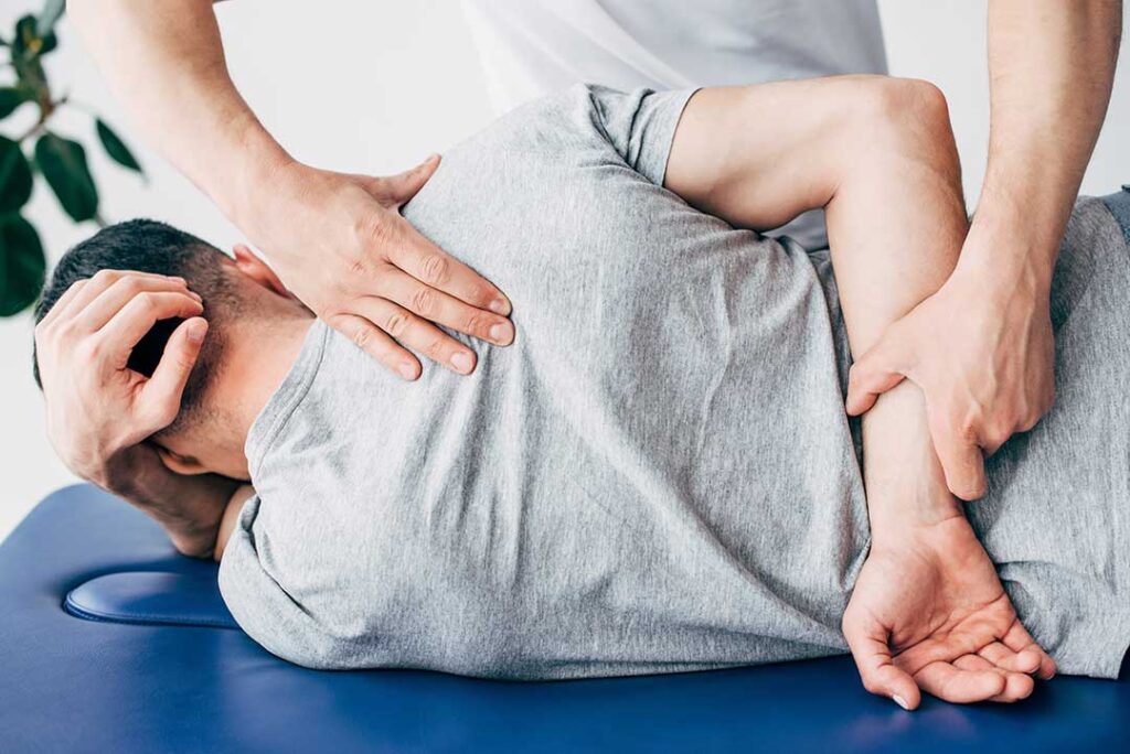 Person doing gentle stretching beside a table with vegetables, a heating pad, and a cold pack nearby.
